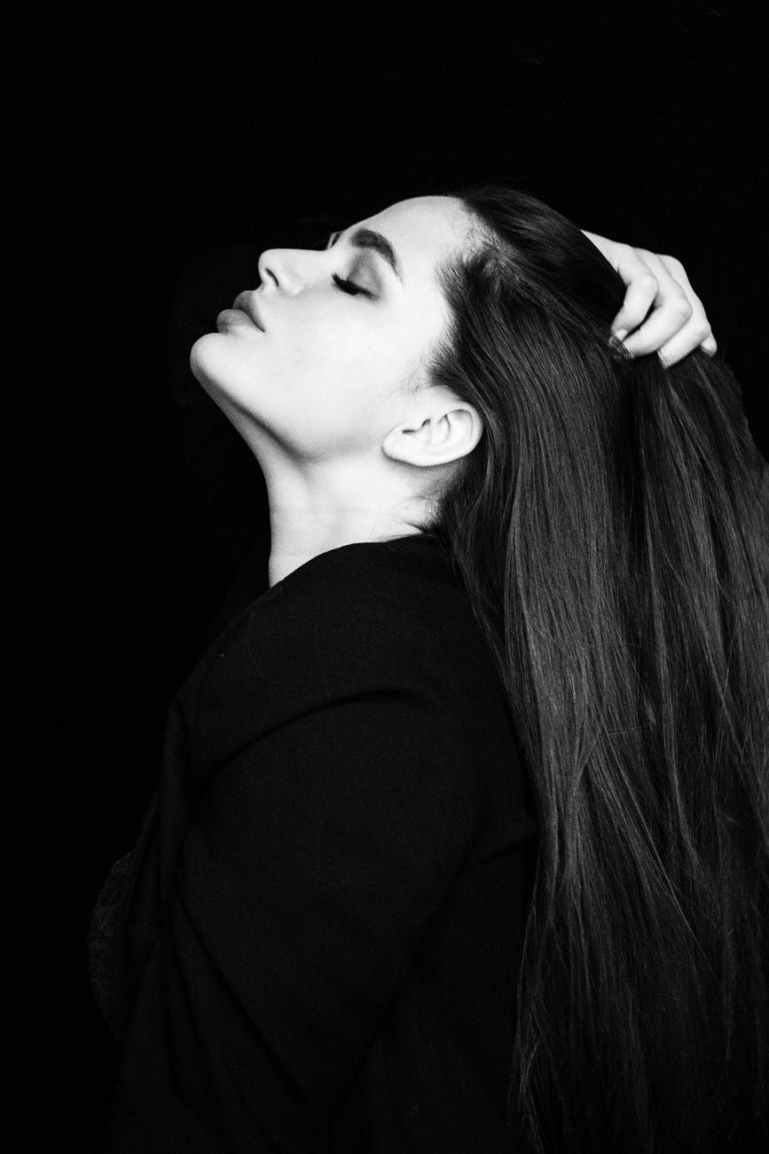 grayscale photo of woman with her eyes closed touching her hair