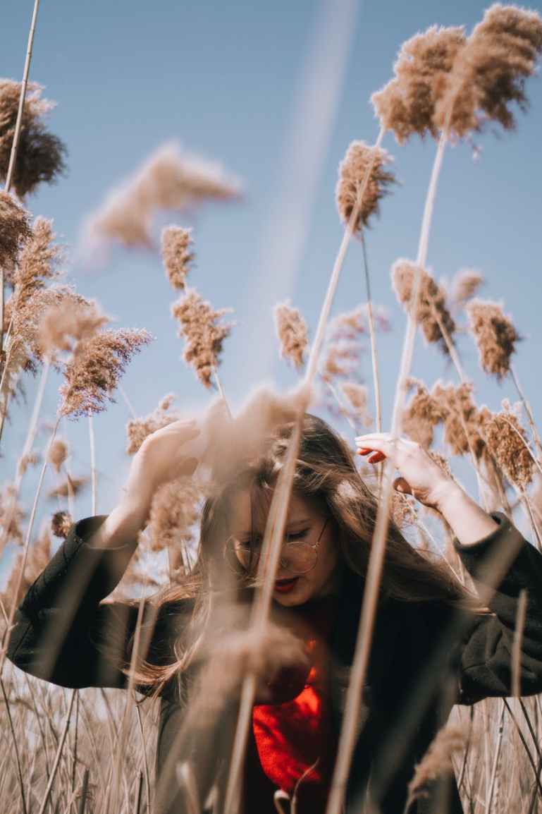 woman in black jacket standing near brown plants