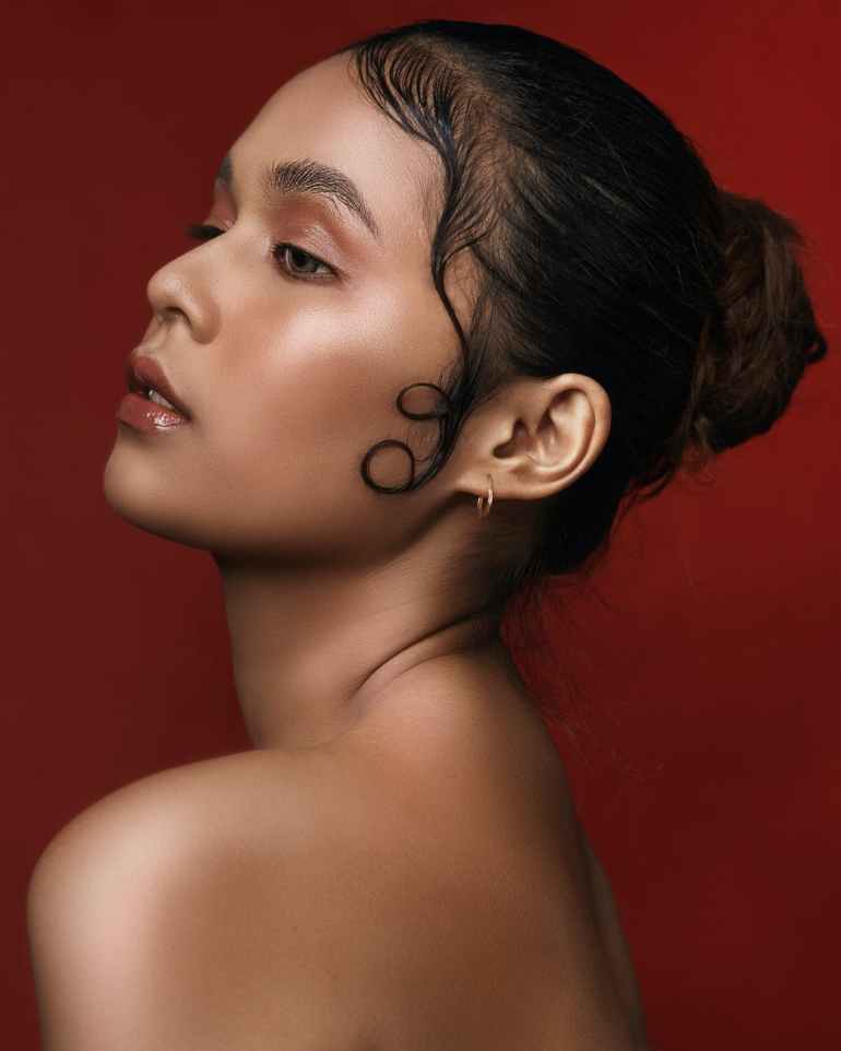 side view photo of topless girl posing in front of red background