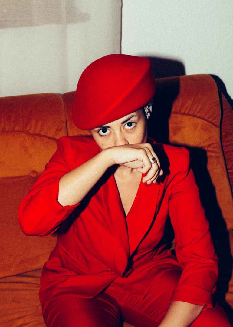 fashionable ethnic woman in cozy armchair at home