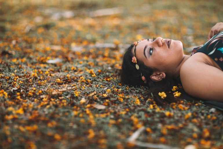 photo of woman in flower crown lying down on the ground