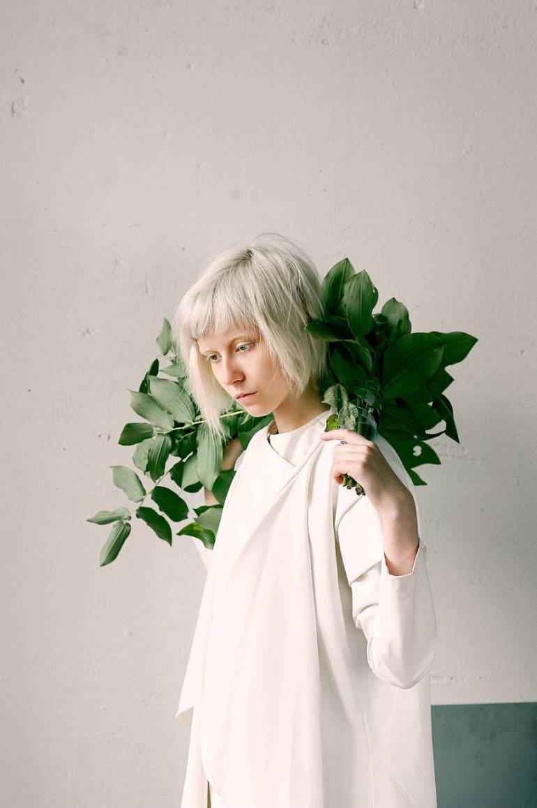 photography of a woman holding green leaves